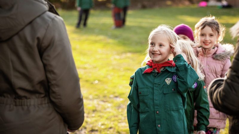 Pige saluterer ældre spejder